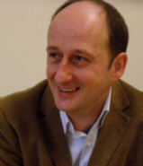 Portrait eines Mannes mit braunen Sakko und blauem Hemd